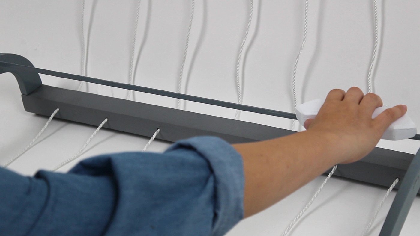 inquadratura sulla mano che muove la navetta del telaio interattivo